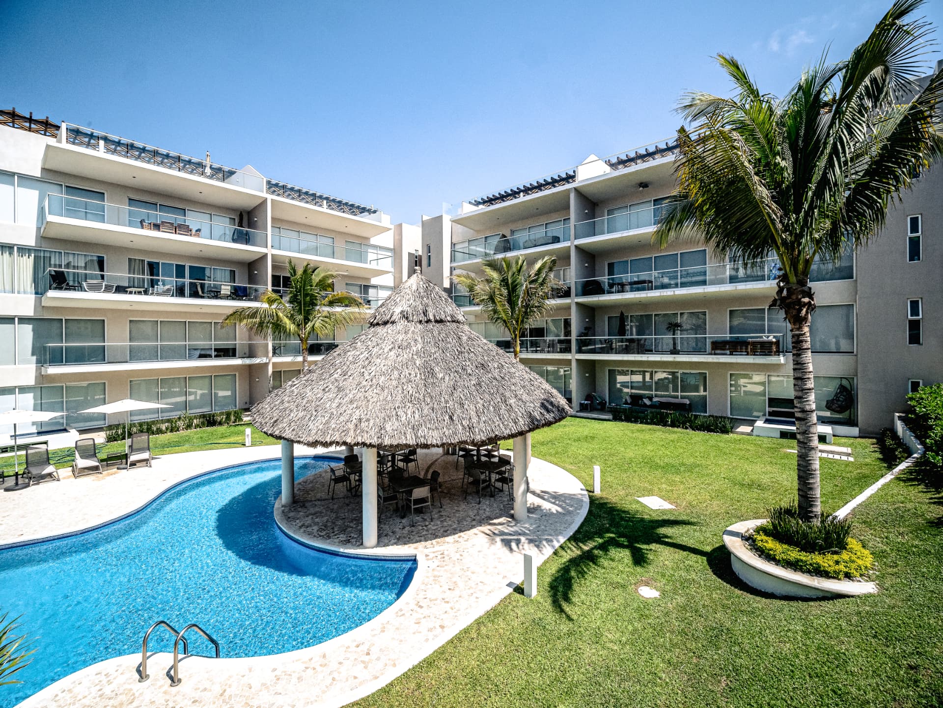 Patio central con alberca, palapa y áreas verdes de VidaMar